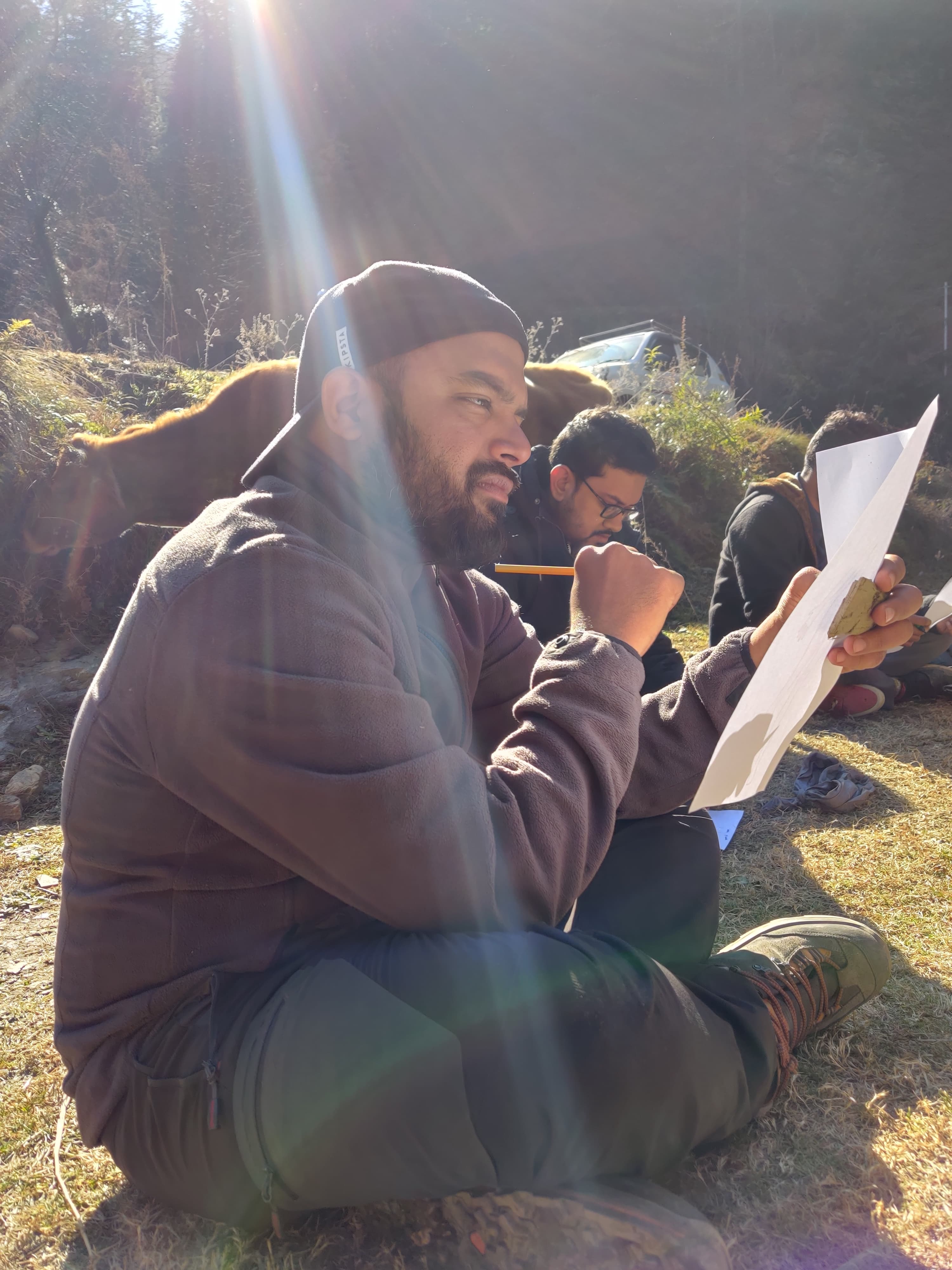 A person sitting in the sun, writing on a sheet of paper