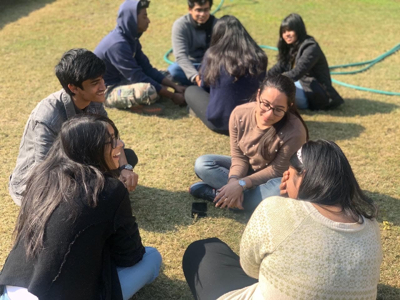 A group sitting in a circle on the grass, mid-conversation