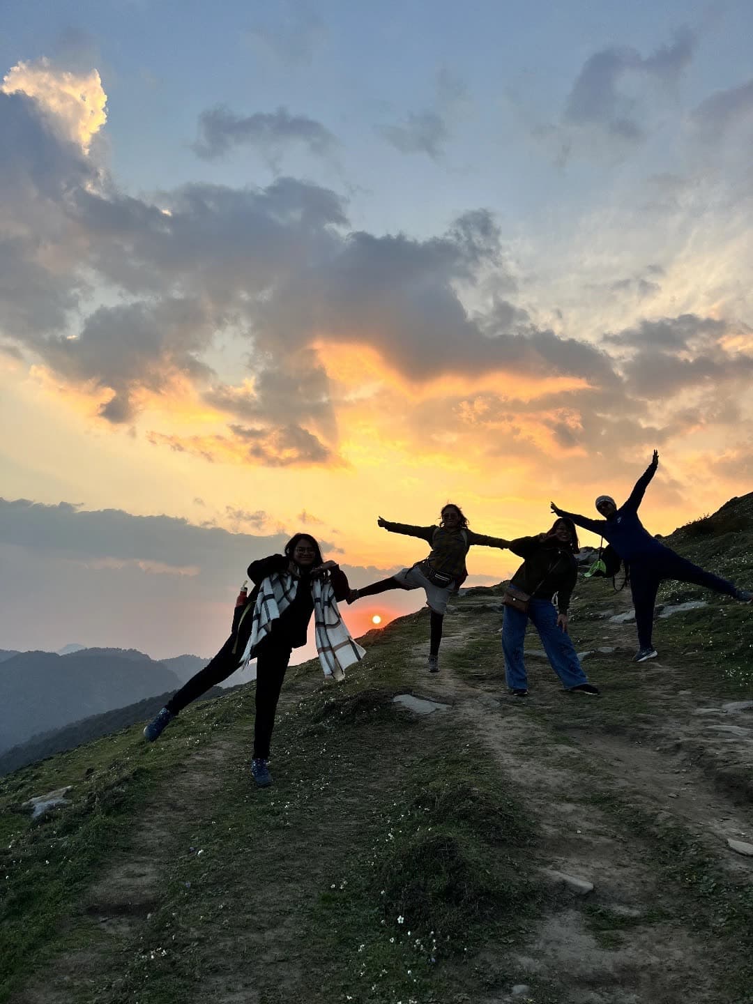 Friends silhouetted against a sunset, striking goofy poses on a mountain trail
